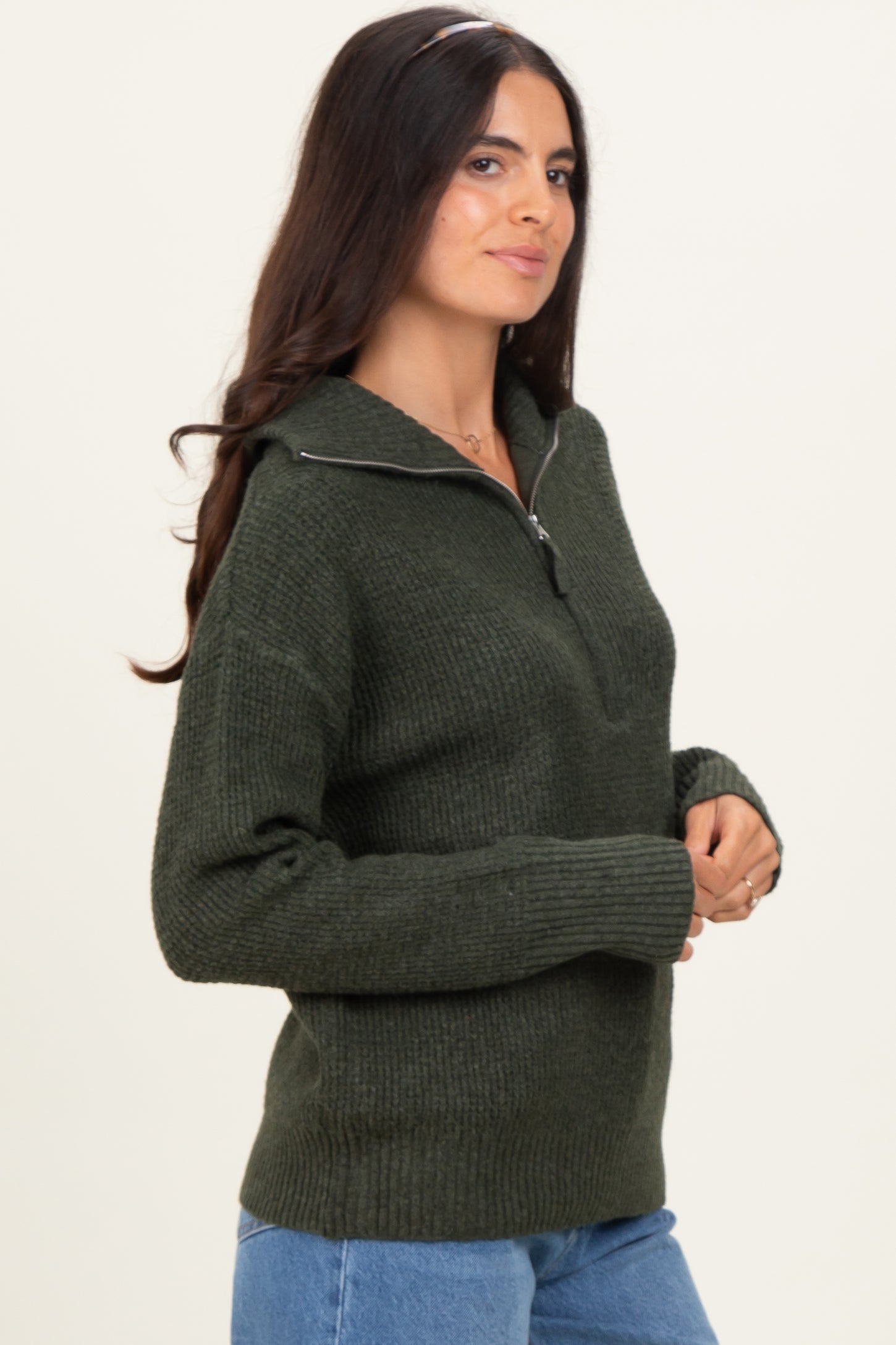woman wearing a dark green zip-up sweater with ribbed detailing and long sleeves