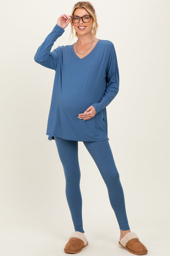 woman wearing a blue maternity loungewear set with a v-neck top and leggings, showing her baby bump