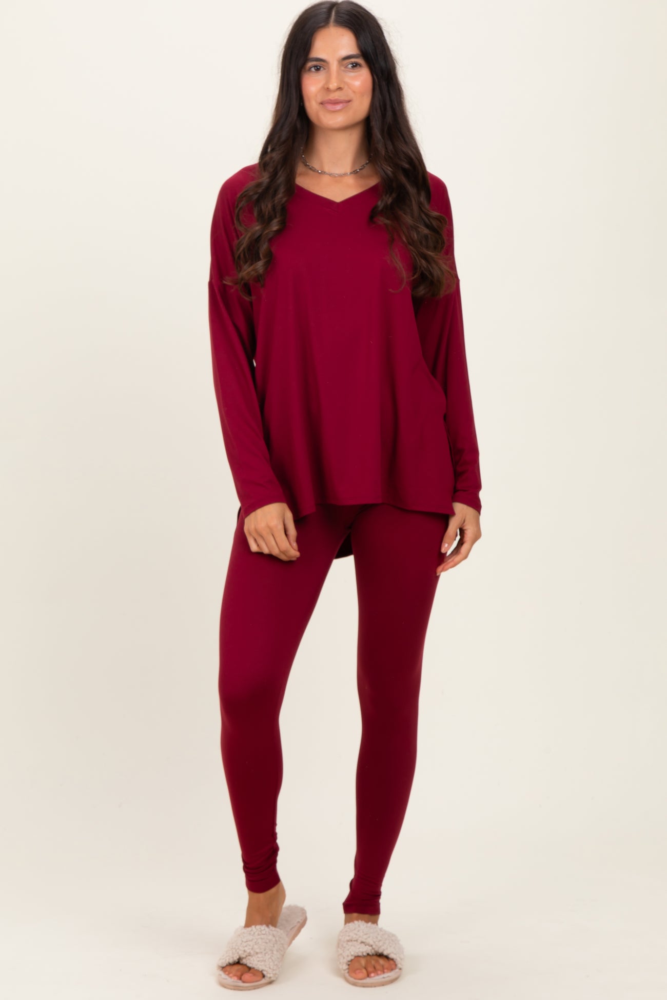 woman wearing a burgundy long sleeve top and matching leggings with cozy slippers on her feet