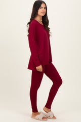 woman wearing a burgundy long sleeve top and matching leggings, styled with cozy slippers