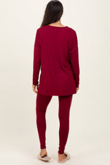 woman wearing a maroon long sleeve top and matching leggings, standing with her back to the camera