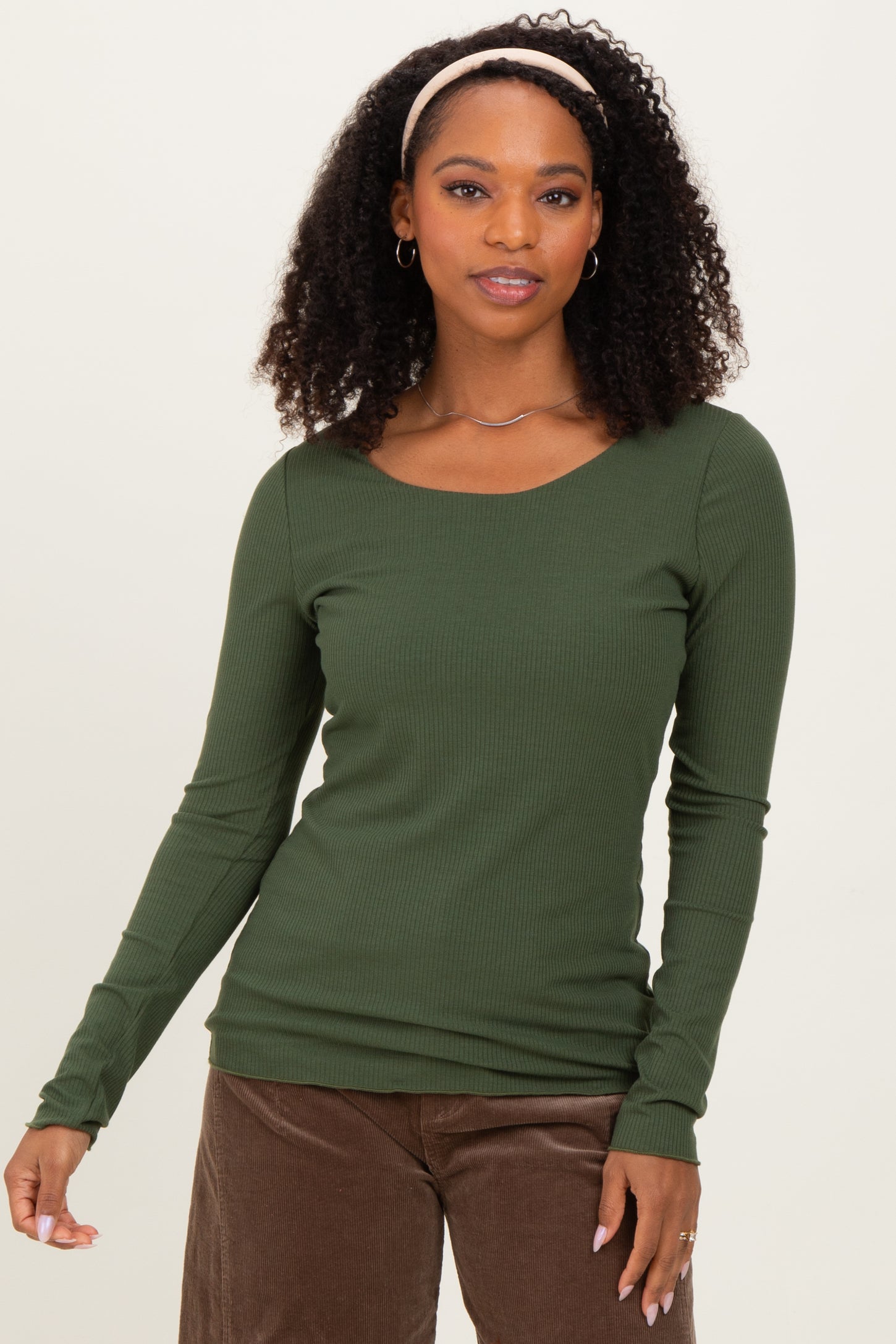 woman wearing a dark green long sleeve ribbed top with a scoop neckline and styled hair