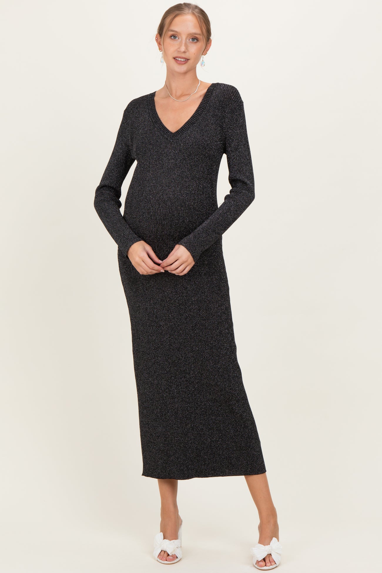 woman wearing a dark shimmer knit maternity dress with a v-neck and long sleeves, showing her baby bump