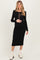 woman wearing a black ribbed maternity dress with long sleeves and sheer panel, holding her baby bump