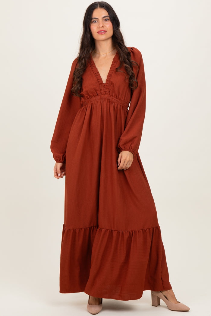 woman wearing an autumn rust long sleeve maxi dress with a deep v-neck and tiered hem