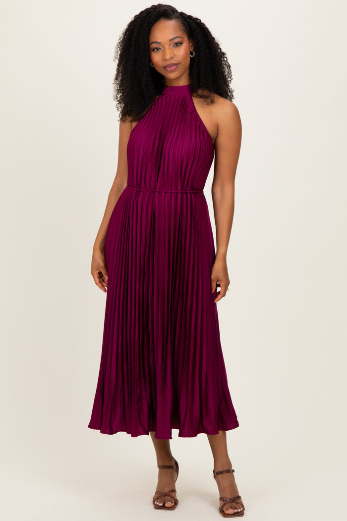 woman wearing a plum pleated halter neck midi dress with a fitted waist and relaxed skirt