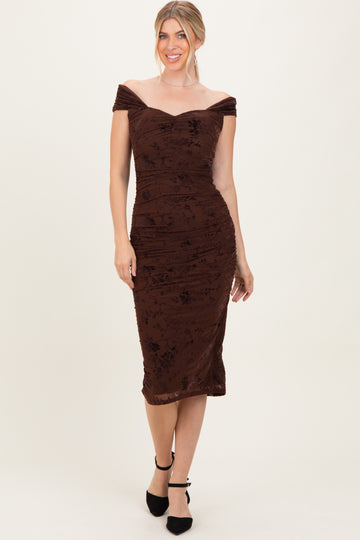 woman wearing a brown off-shoulder fitted dress with floral patterns and ruching details, styled with black heels