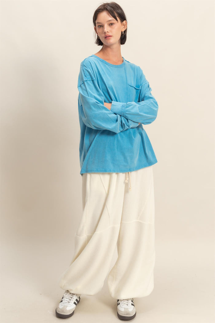 woman wearing a bright blue oversized long sleeve shirt and cream-colored wide-leg pants