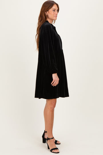 woman wearing a black velvet long sleeve dress with a flowing silhouette and puffed sleeves, paired with black heeled sandals