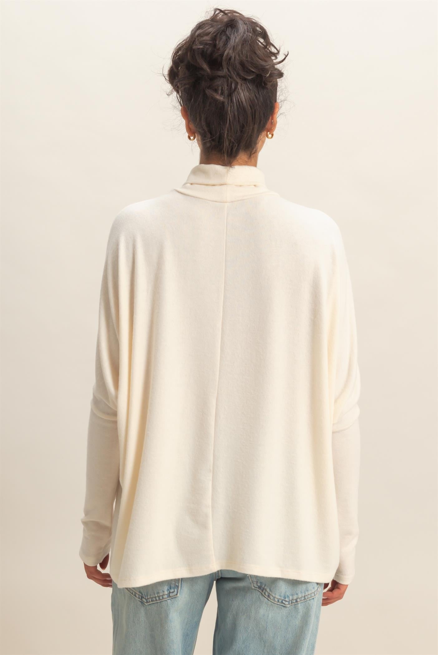 woman wearing a cream oversized long sleeve sweater with a mock neck and relaxed fit