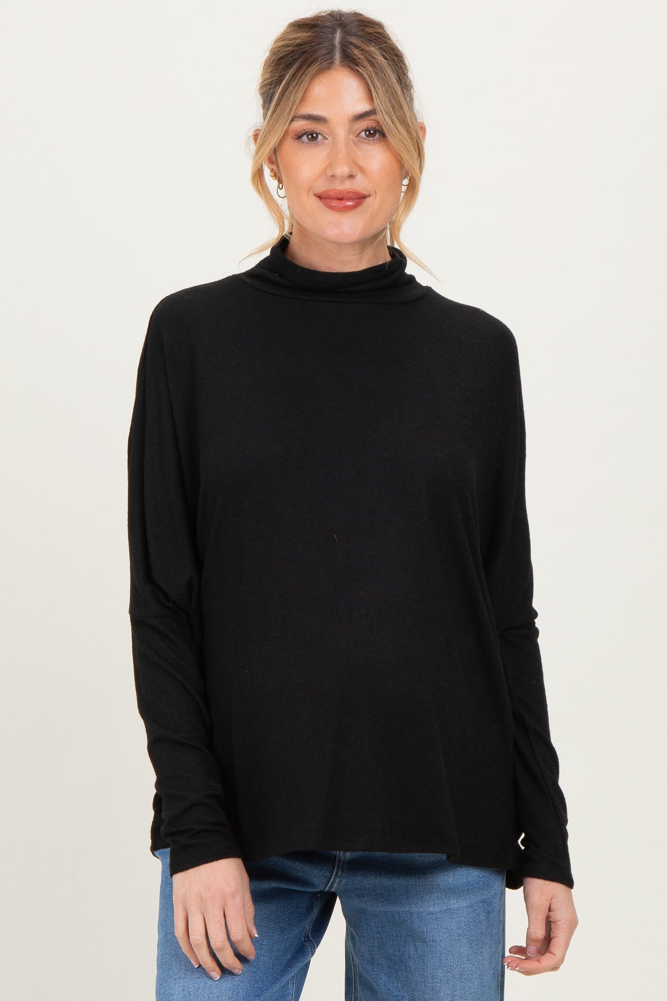 woman wearing a black maternity turtleneck sweater with long sleeves and a relaxed fit, baby bump visible