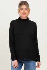 woman wearing a black maternity turtleneck sweater with long sleeves and a relaxed fit, baby bump visible