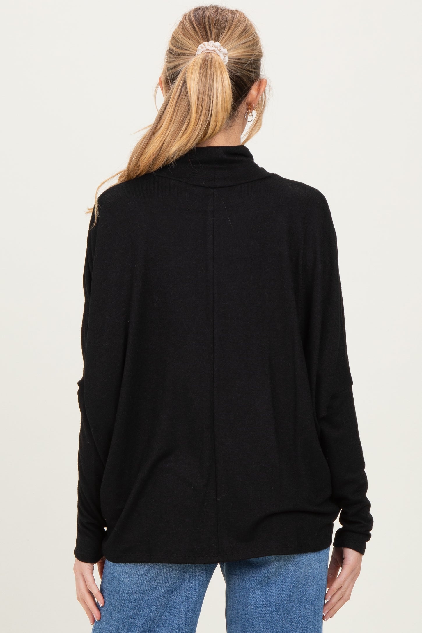 woman wearing a black maternity top with a relaxed fit and long sleeves, seen from the back