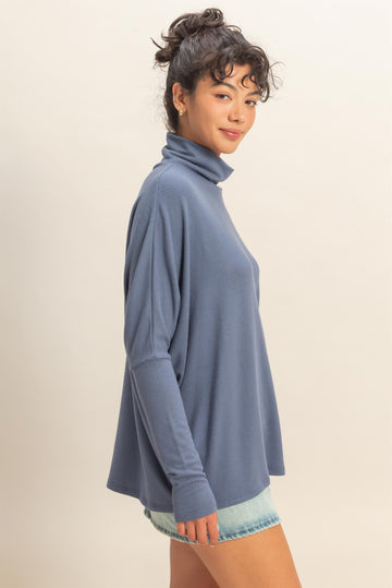 woman wearing a light blue long sleeve turtleneck top paired with denim shorts