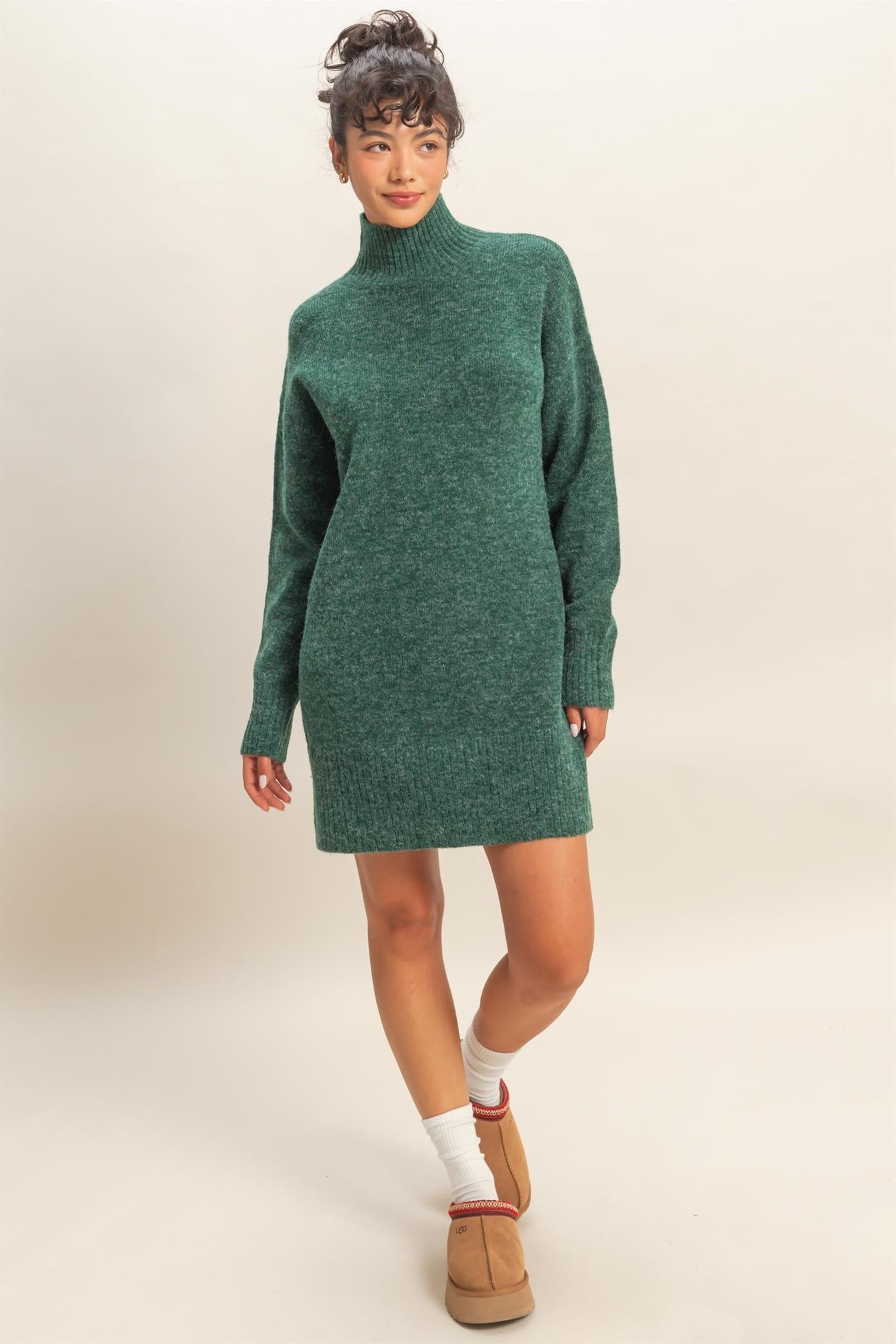woman wearing a green knitted sweater dress with a high neck and long sleeves, styled with cozy footwear