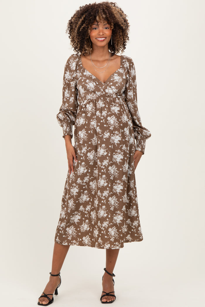 woman wearing a brown floral maternity dress with long sleeves and a v-neckline, showcasing a baby bump