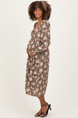 woman wearing a brown floral maternity dress and cradling her baby bump
