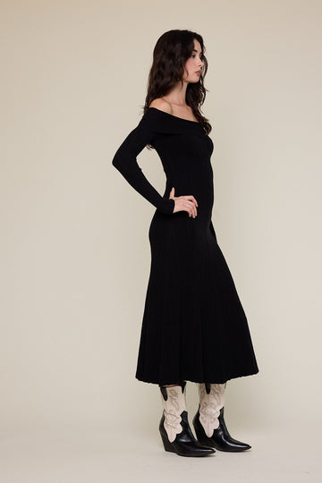 woman wearing a black ribbed off-shoulder maxi dress paired with white floral-embroidered cowboy boots