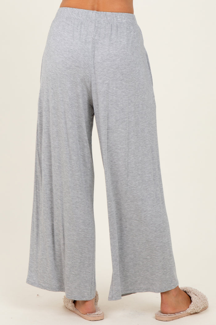 woman wearing light gray wide-leg lounge pants, standing with back to the camera, paired with cozy slippers