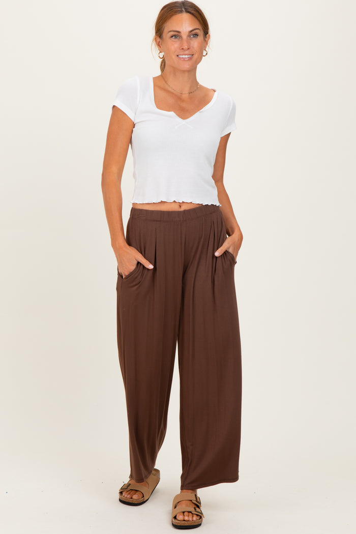woman wearing a white short sleeve crop top and brown wide-leg pants with pockets