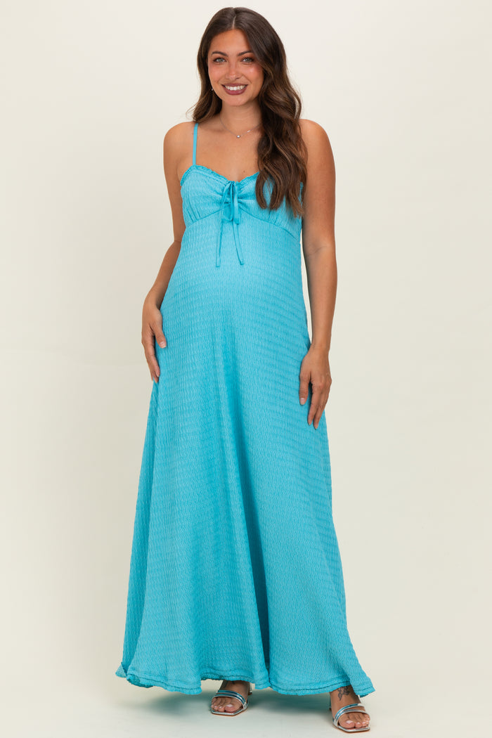 woman wearing a turquoise maternity maxi dress with a tie detail and a visible baby bump