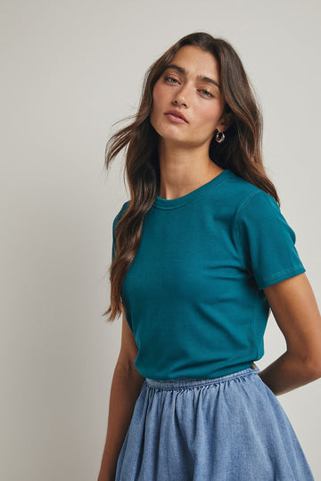 woman wearing a teal short sleeve t-shirt paired with a denim skirt