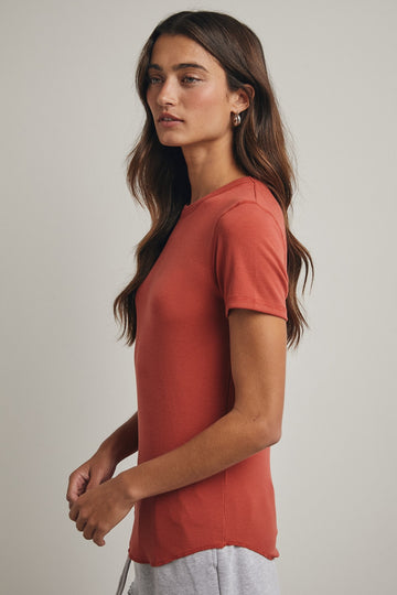 woman wearing a rust short sleeve t-shirt with a fitted style and subtle ribbed texture