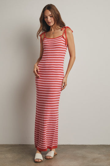 woman wearing a red and pink striped maxi dress with adjustable tie straps and a fitted silhouette