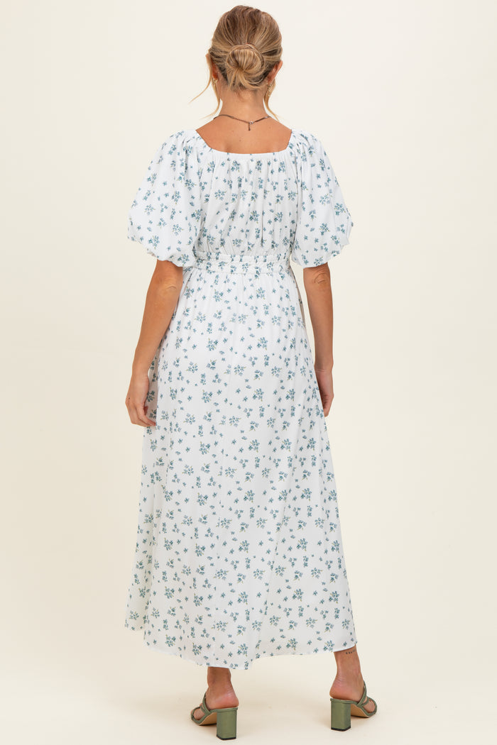 woman wearing a white floral maternity maxi dress with puff sleeves and a cinched waist, showing her back