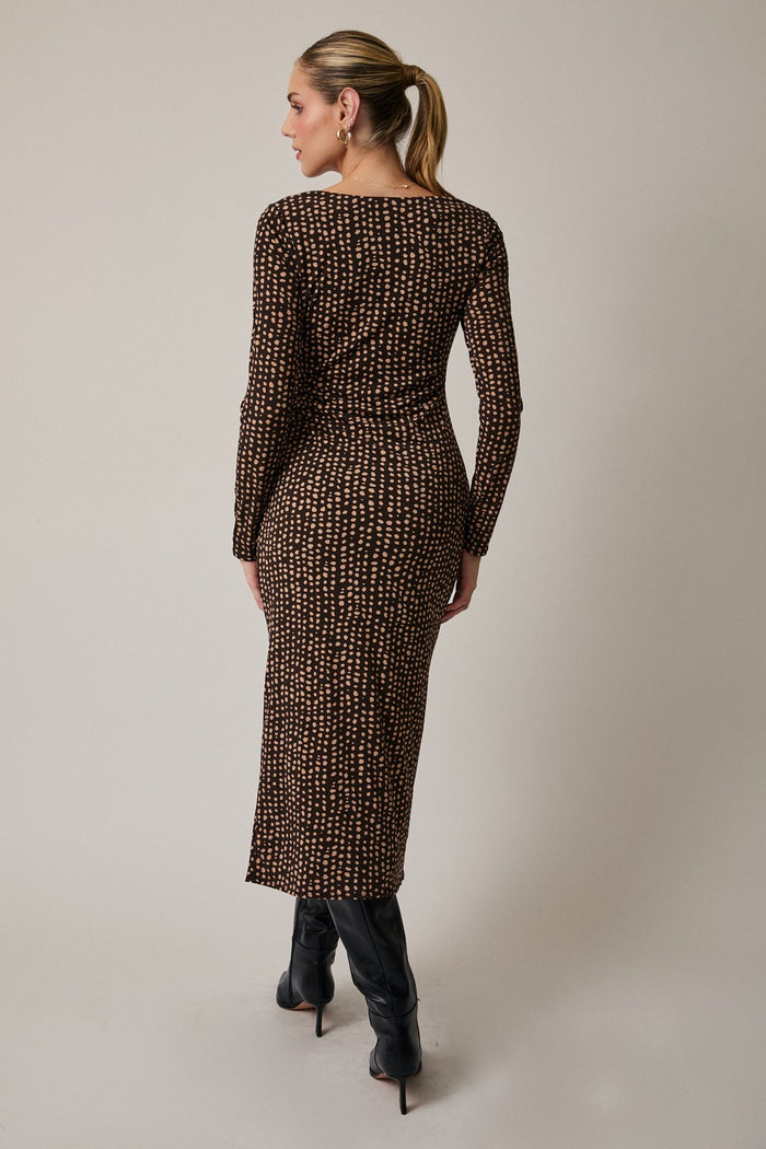 woman wearing a fitted brown midi dress with a geometric print and long sleeves, viewed from the back
