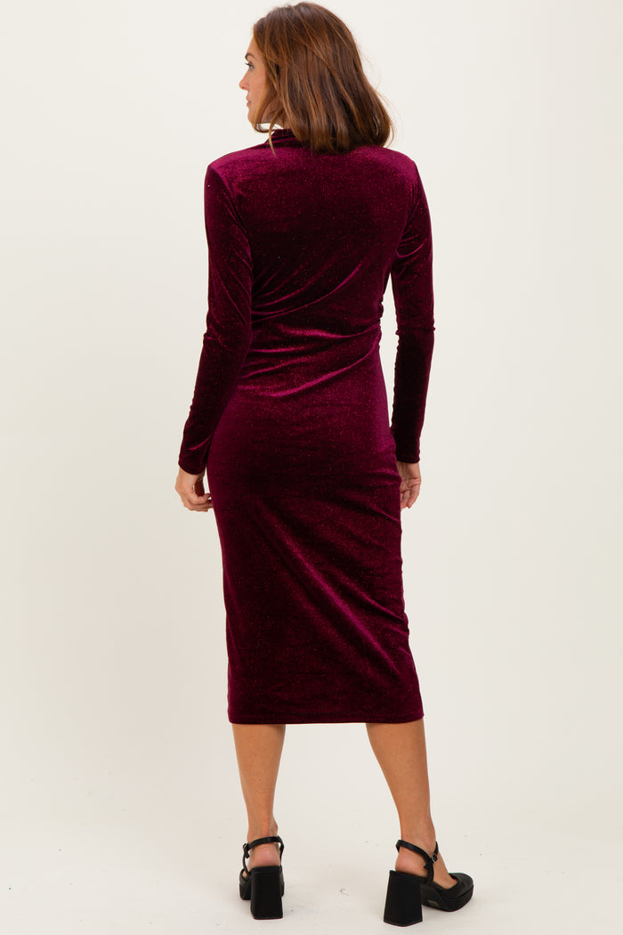 woman wearing a burgundy velvet long sleeve midi dress, viewed from the back, with fitted silhouette and below-the-knee length
