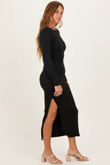 woman wearing a black long sleeve midi dress with side slits and fitted silhouette, standing sideways