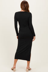 woman wearing a black long sleeve fitted maxi dress with a side slit, viewed from the back