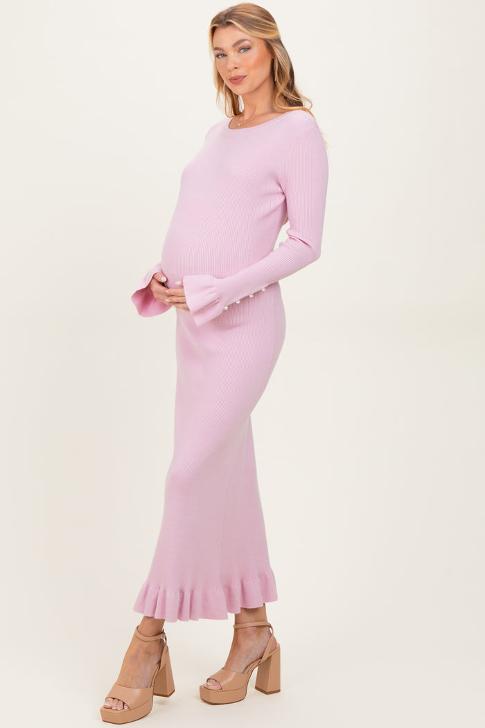 woman wearing a light pink ribbed maternity dress with a ruffled hem and bell sleeves, showing her baby bump