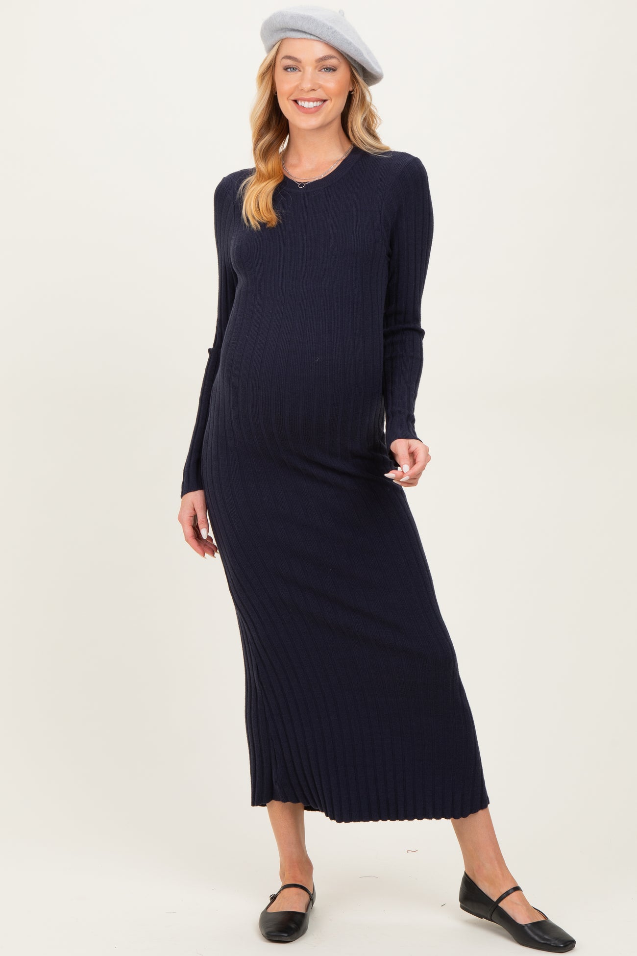 woman wearing a navy ribbed maternity maxi dress and a beret, showcasing her baby bump