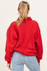 woman wearing a red oversized maternity sweatshirt with a high collar and long sleeves