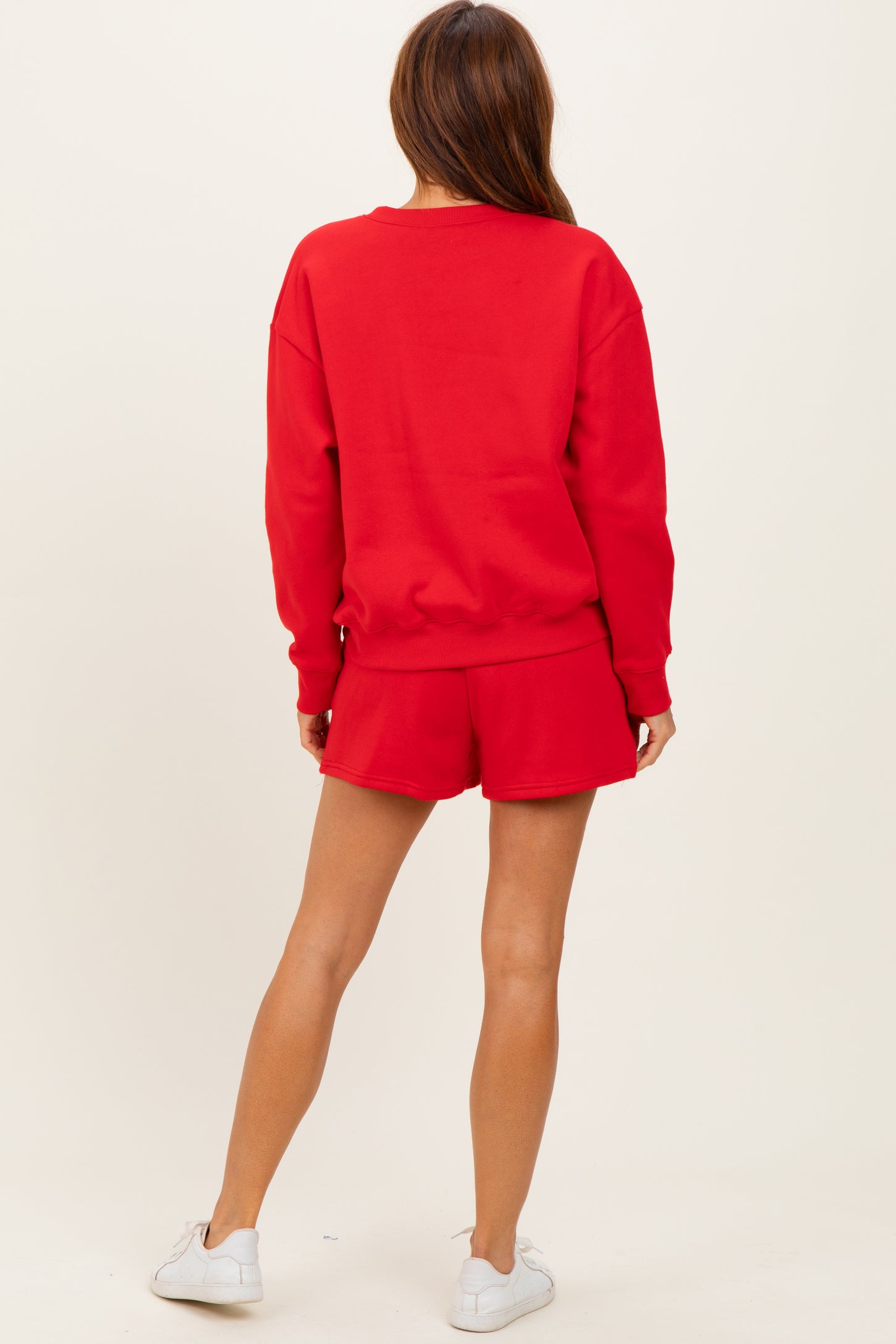 woman wearing a red oversized sweatshirt and matching red shorts, standing with her back to the camera