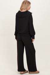 woman wearing a black ribbed hoodie and matching wide-leg pants, viewed from the back