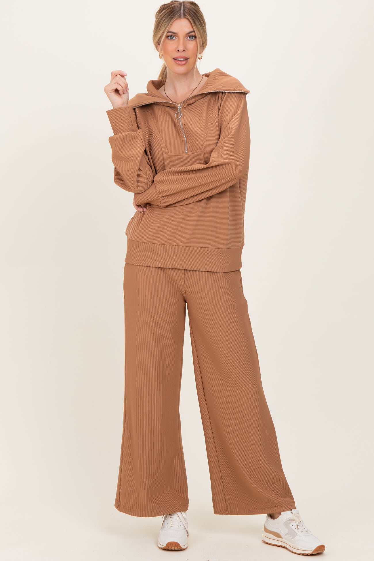 woman wearing a tan ribbed loungewear set with a zip-up hoodie and wide-leg pants