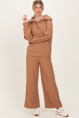 woman wearing a tan ribbed loungewear set with a zip-up hoodie and wide-leg pants