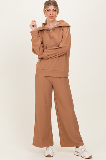 woman wearing a tan ribbed loungewear set with a zip-up hoodie and wide-leg pants