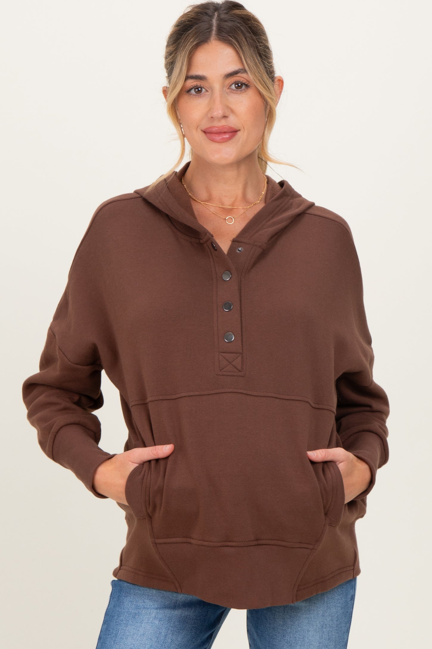 woman wearing a brown maternity hoodie with a button-up neckline and front pocket