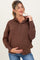 woman wearing a brown maternity hoodie with buttons, holding her baby bump