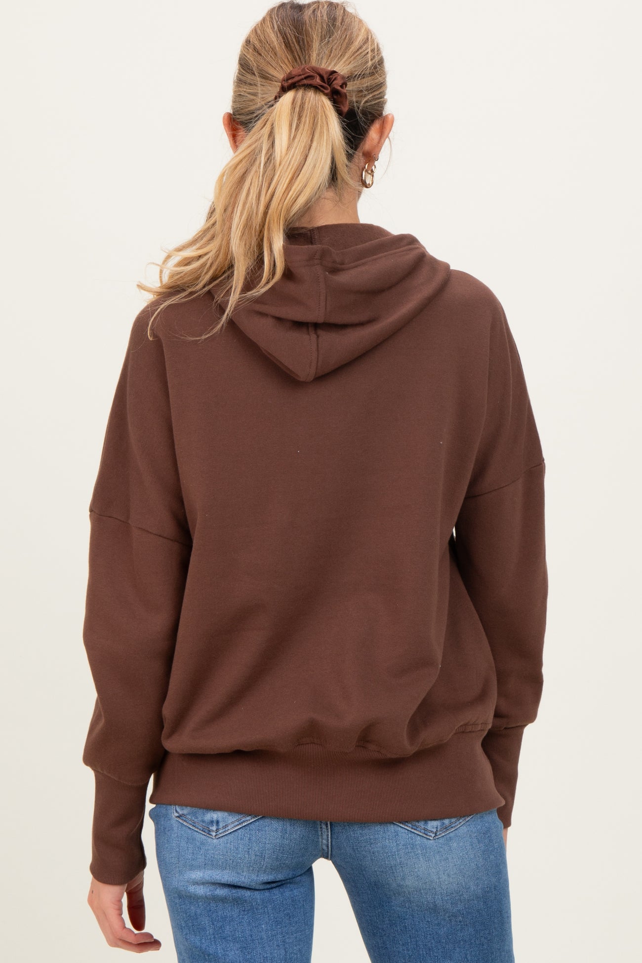 woman wearing a brown maternity hoodie with a relaxed fit and hood, showing a stylish back view