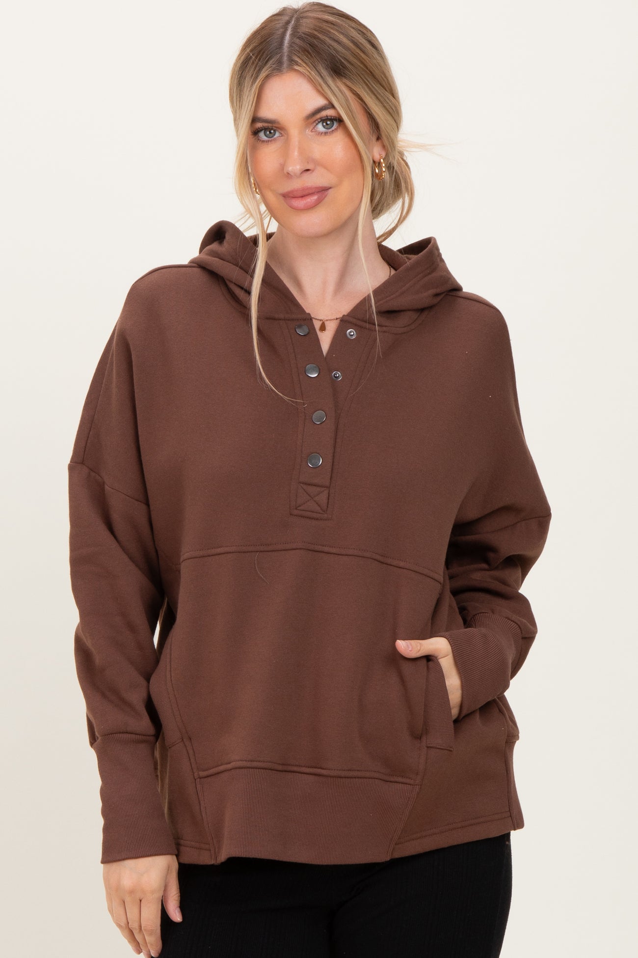woman wearing a brown long sleeve hooded sweatshirt with button details and a front pocket