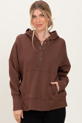 woman wearing a brown long sleeve hooded sweatshirt with button details and a front pocket