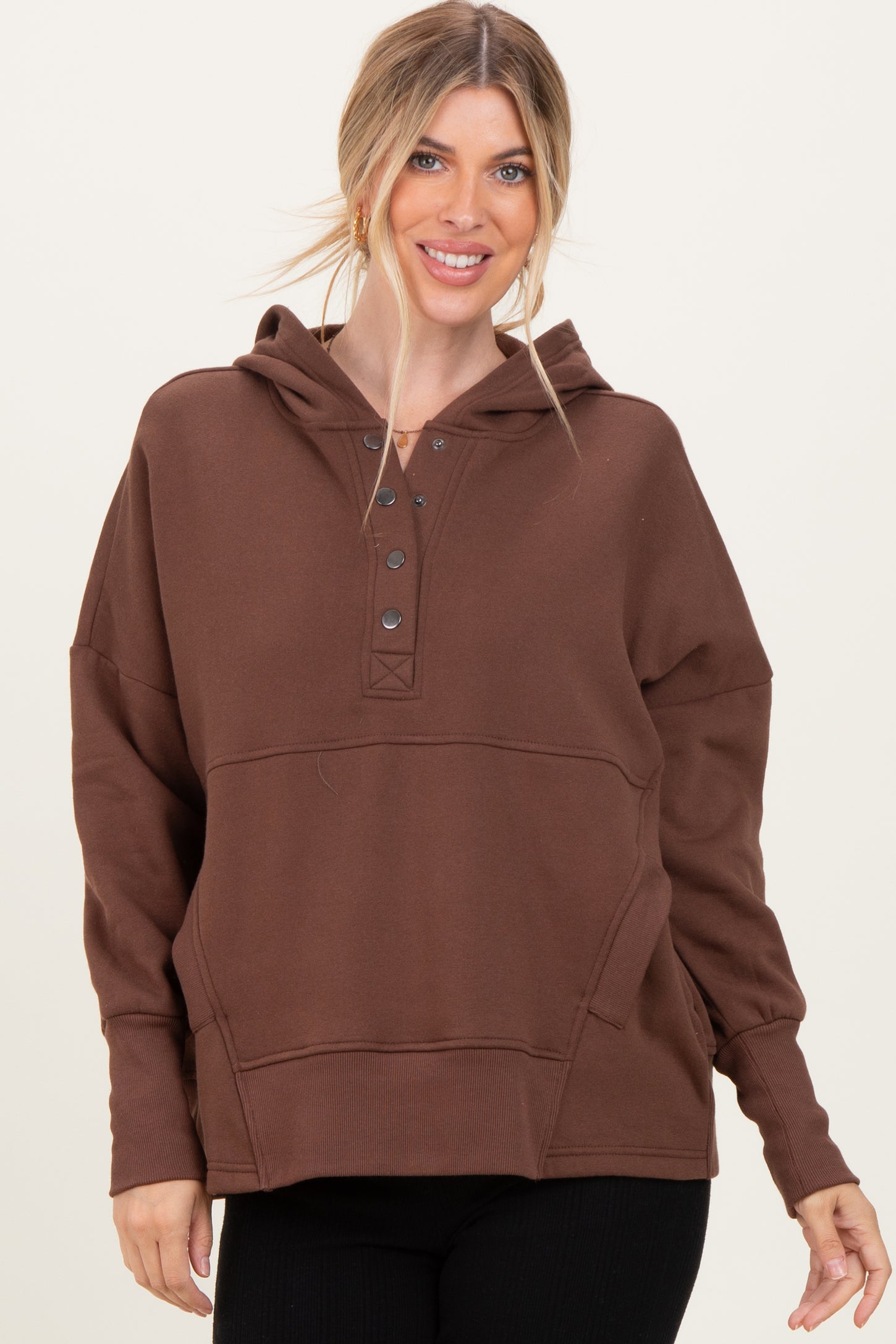 woman wearing a brown oversized hoodie with a buttoned placket and a kangaroo pocket