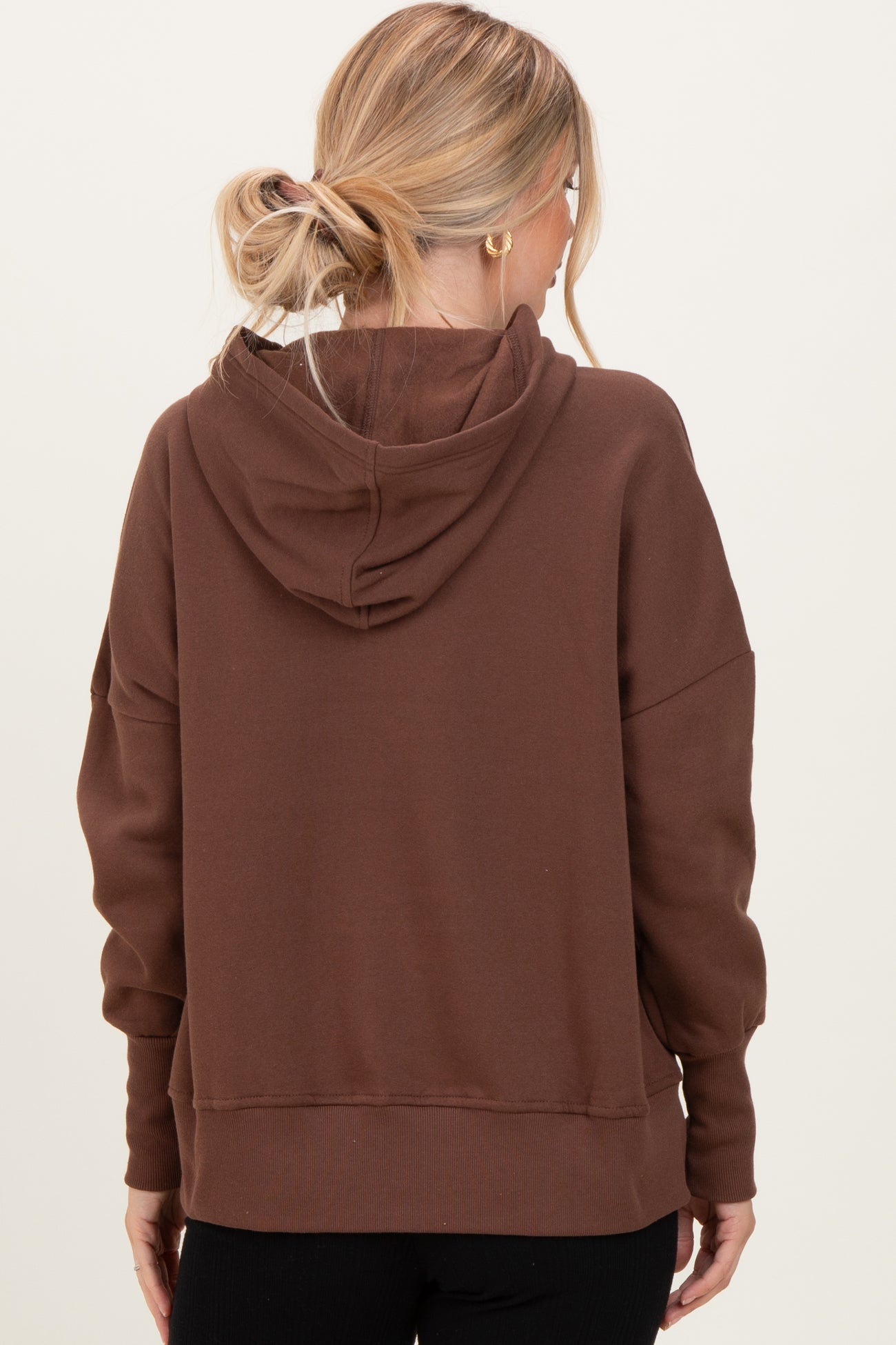 woman wearing a brown oversized hoodie with a hood and dropped shoulders, showing the back view