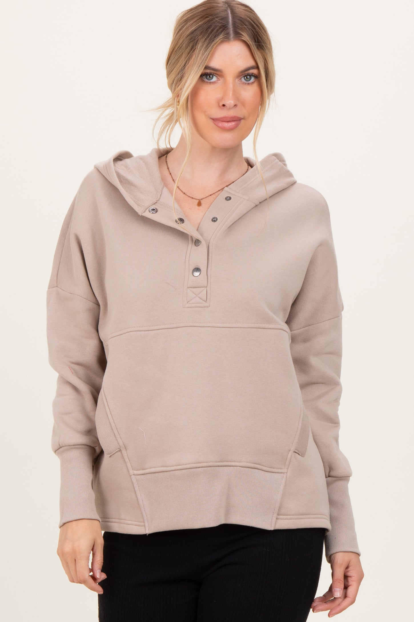 woman wearing a taupe hooded sweatshirt with a buttoned placket and front pocket