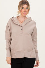 woman wearing a taupe hooded sweatshirt with a buttoned placket and front pocket